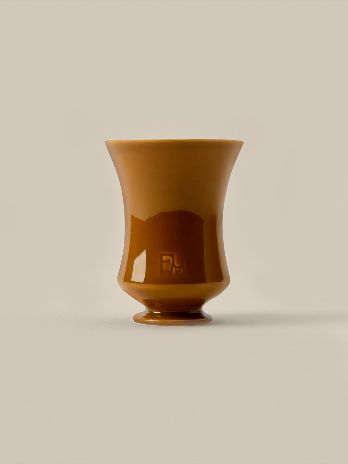 Amber ceramic Fume candle vessel on a beige background