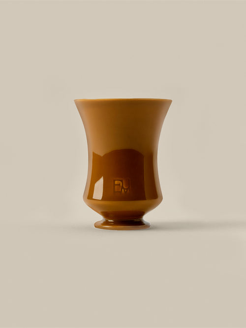 Amber ceramic Fume candle vessel on a beige background