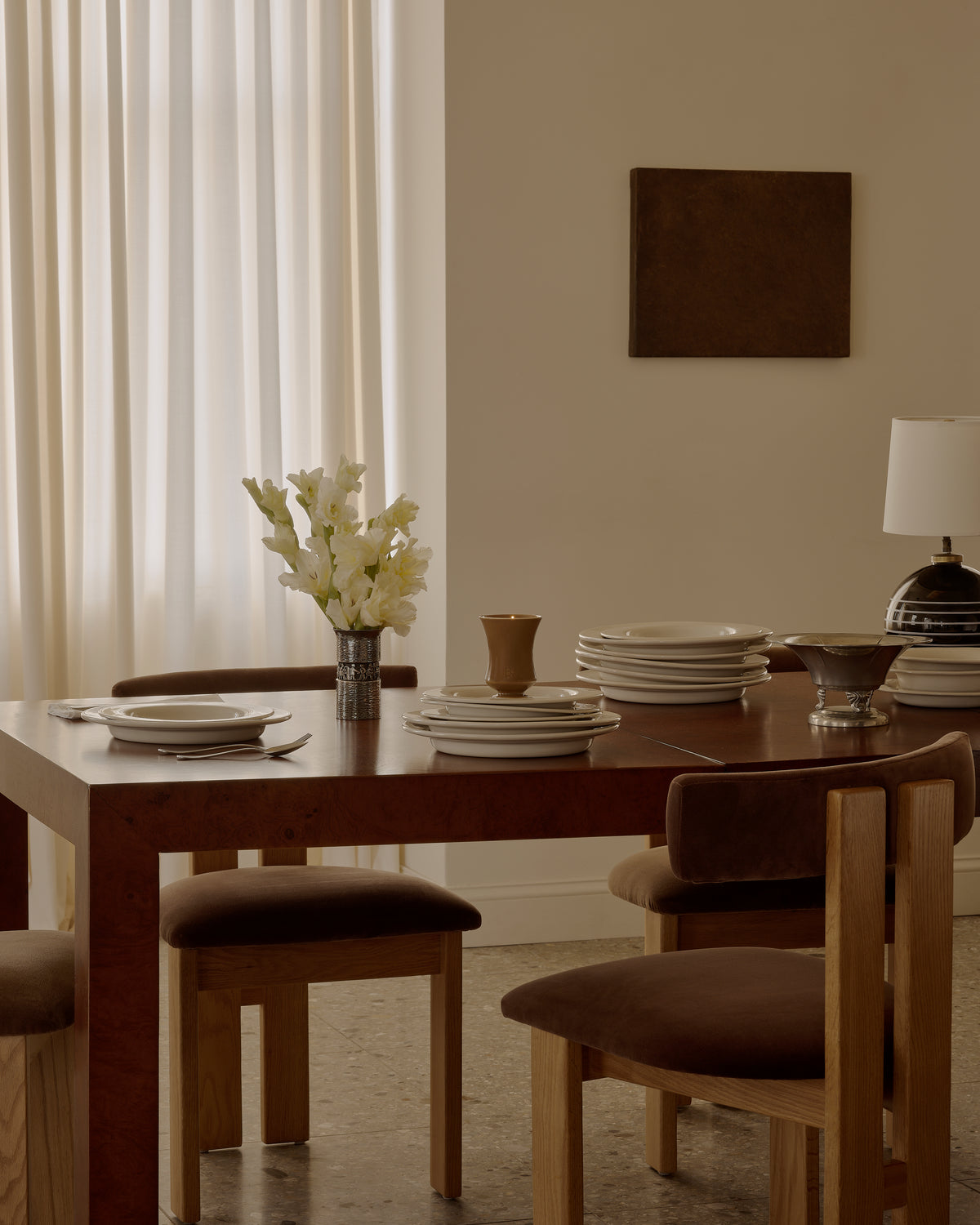 Lit Ambered Apple candle on a dining table set with plates, cutlery, flowers, and framed art on the wall
