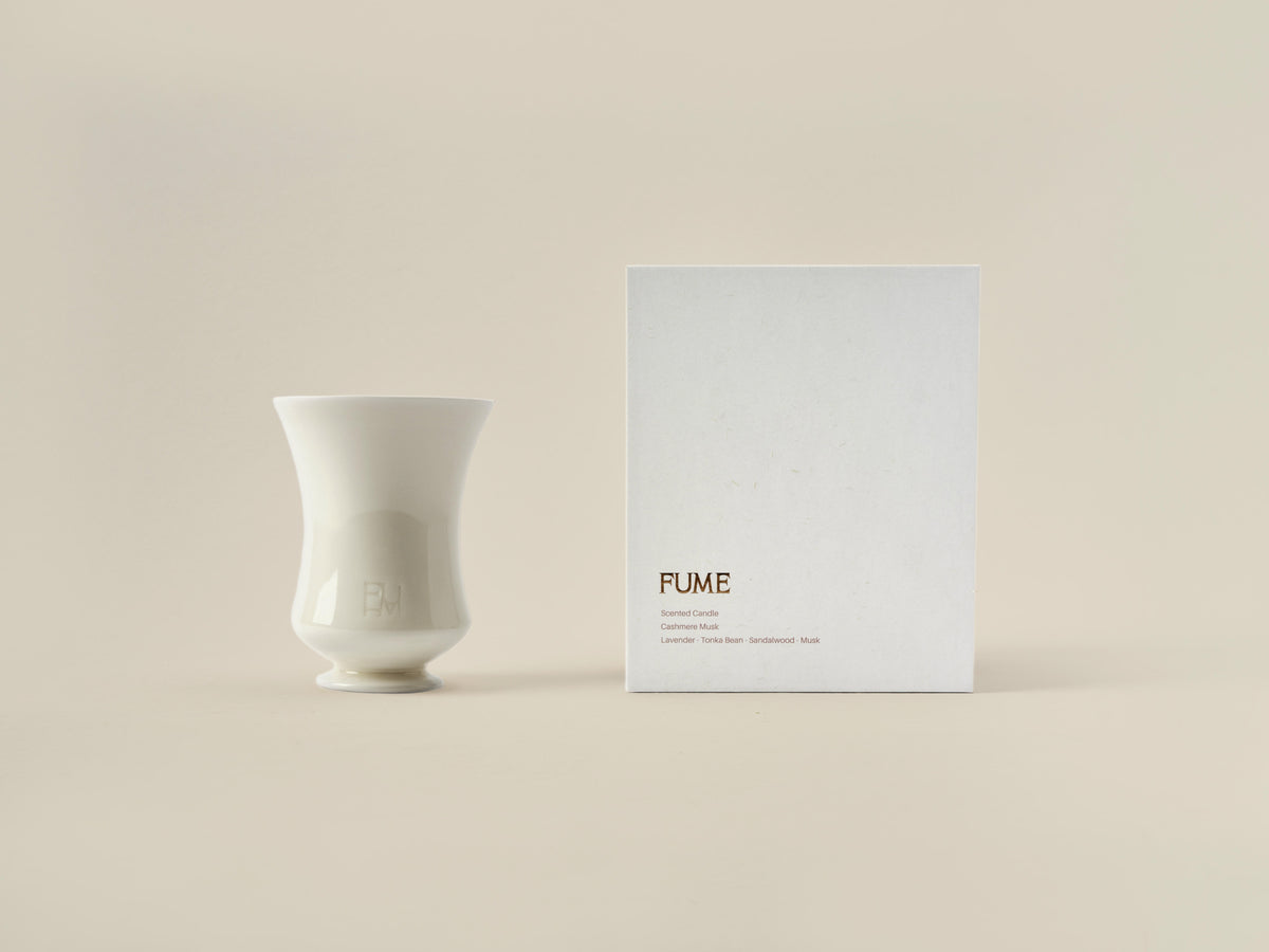 Cashmere Musk candle beside its closed Fume gift box on a beige background