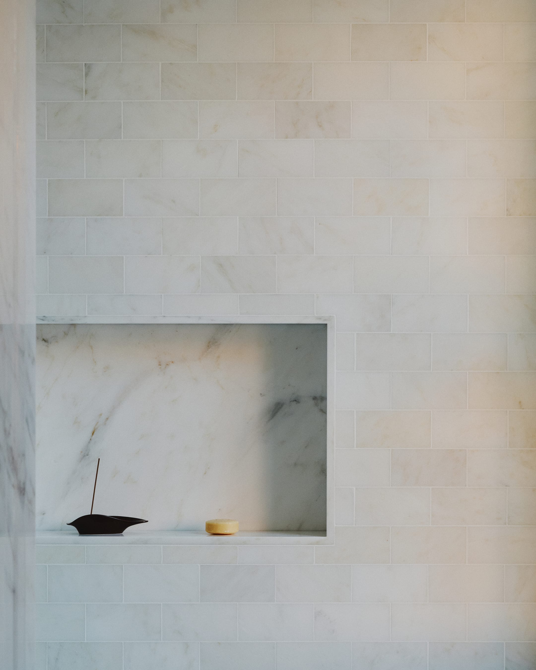 Marble fireplace with a small black incense holder and a yellow candle on a white background
