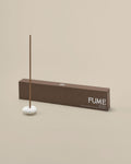 Incense stick with a white base and 'FUME' branding on a beige background