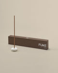 Incense stick with a white base and 'FUME' branding on a beige background