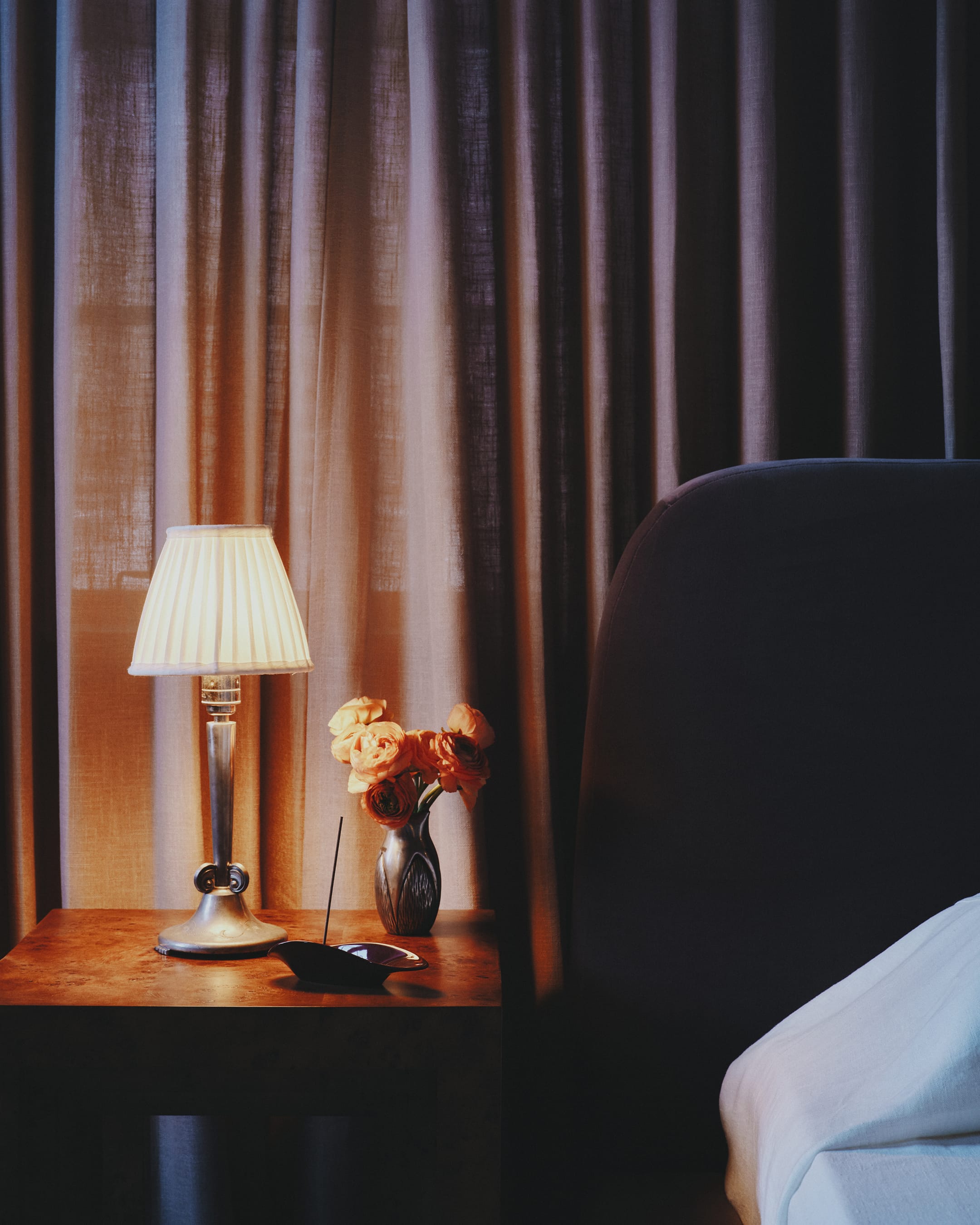 Lamp and vase on a nightstand with curtains in the background